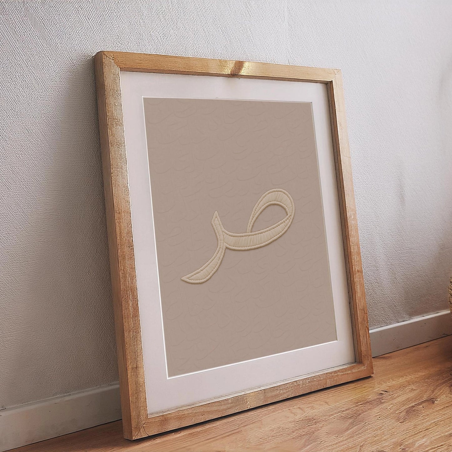 Islamisches Poster mit arabischem Kalligrafie-Buchstaben in Stickerei-Optik, minimalistisches Wandbild auf beigem Hintergrund im Holzrahmen – moderne muslimische Wanddeko.